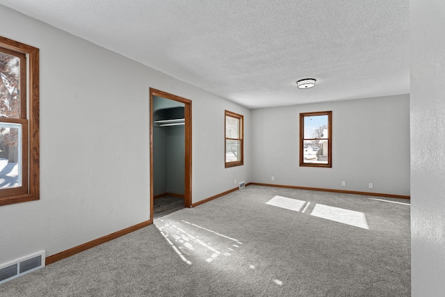 empty room with carpet floors and a textured ceiling