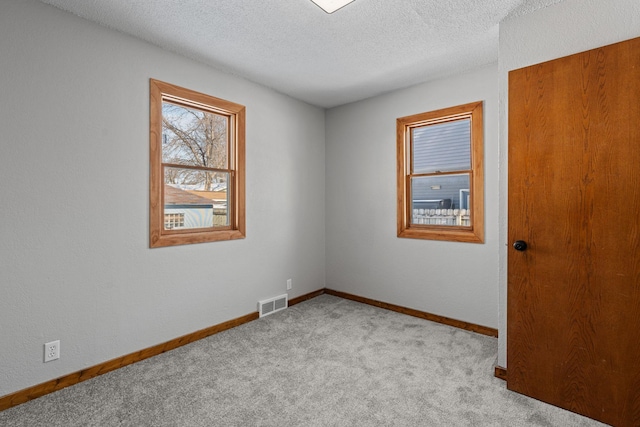 spare room featuring a textured ceiling and light colored carpet