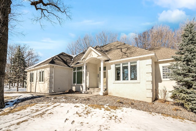 ranch-style home with roof with shingles and stucco siding