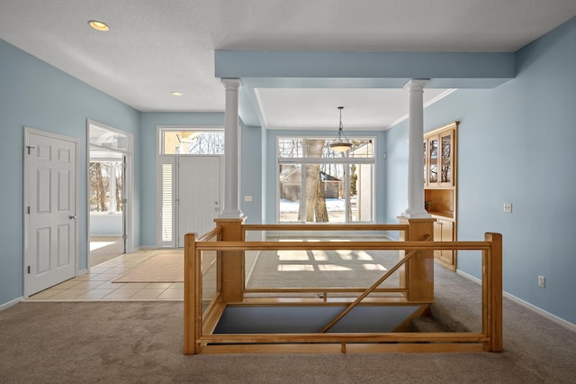 tiled entryway featuring decorative columns, baseboards, and carpet flooring