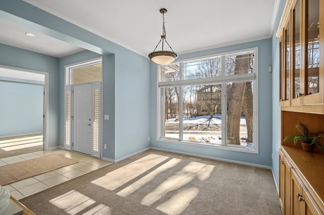 unfurnished dining area with light tile patterned flooring, light colored carpet, baseboards, and ornamental molding