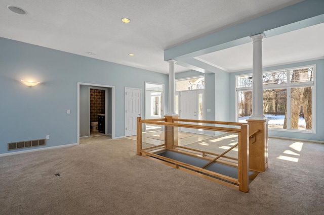 carpeted spare room with recessed lighting, decorative columns, baseboards, and visible vents