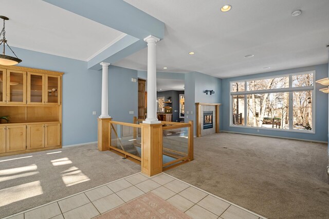 unfurnished living room with light carpet, a tiled fireplace, recessed lighting, light tile patterned flooring, and decorative columns