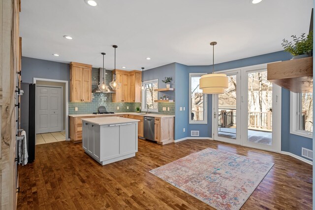 kitchen featuring a wealth of natural light, a sink, gas stovetop, wall chimney exhaust hood, and light countertops