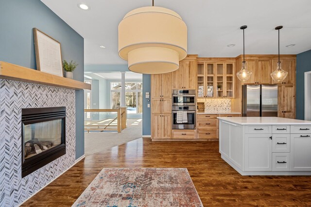 kitchen with appliances with stainless steel finishes, light countertops, glass insert cabinets, and dark wood-style flooring