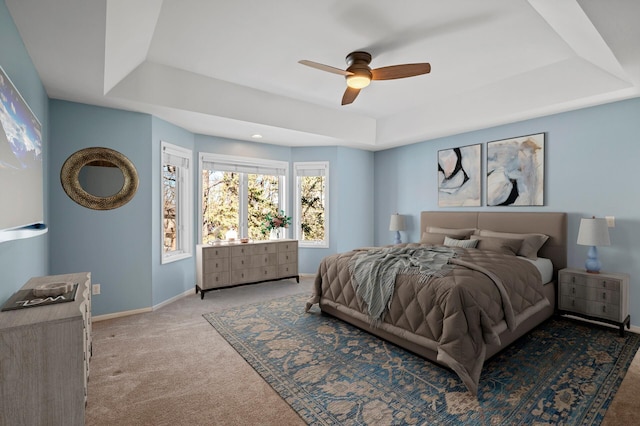 bedroom featuring a tray ceiling, baseboards, ceiling fan, and carpet flooring