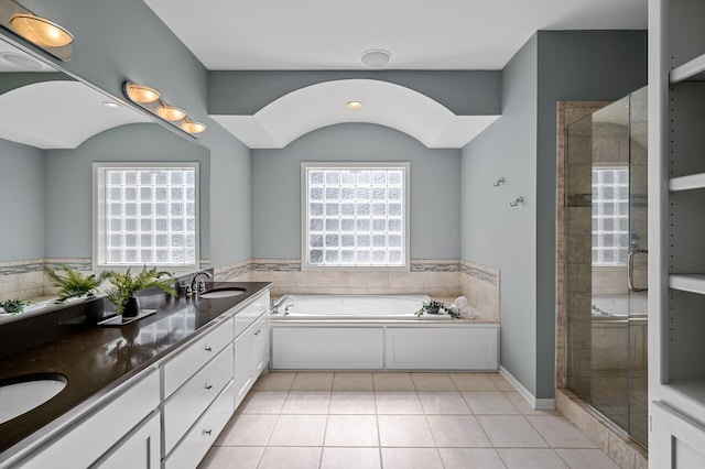 full bathroom featuring double vanity, a stall shower, a sink, tile patterned flooring, and a bath