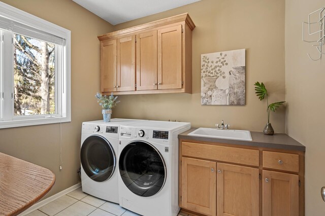 clothes washing area featuring a sink, washer and dryer, cabinet space, light tile patterned flooring, and baseboards