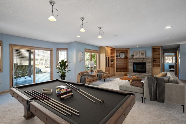 playroom featuring baseboards, recessed lighting, a stone fireplace, a textured ceiling, and carpet flooring