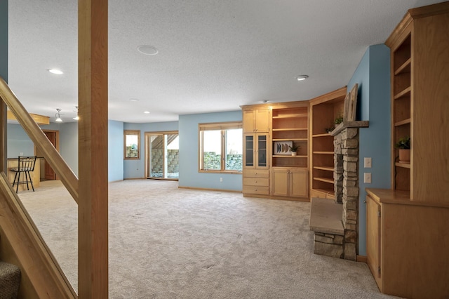 unfurnished living room with a textured ceiling, stairs, baseboards, and light carpet