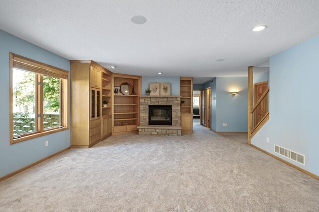 unfurnished living room with visible vents, a textured ceiling, a stone fireplace, and baseboards