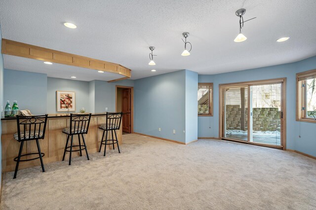 kitchen featuring a kitchen breakfast bar, baseboards, and light colored carpet