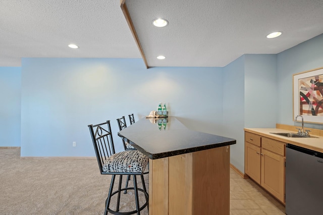 kitchen featuring dishwashing machine, recessed lighting, a kitchen breakfast bar, a textured ceiling, and a sink