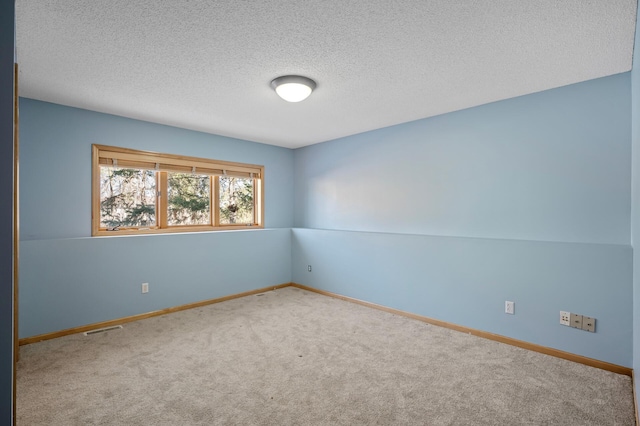 spare room with visible vents, a textured ceiling, baseboards, and carpet