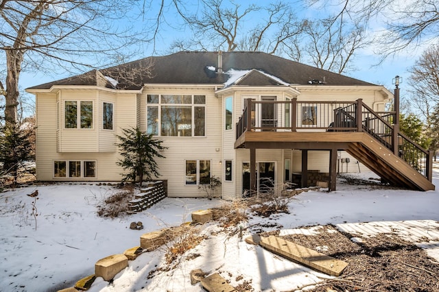 snow covered rear of property featuring stairway and a wooden deck