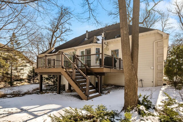 snow covered back of property featuring stairway and a wooden deck