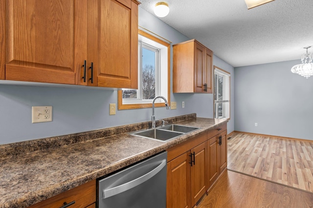 kitchen featuring sink, a textured ceiling, decorative light fixtures, light hardwood / wood-style floors, and stainless steel dishwasher