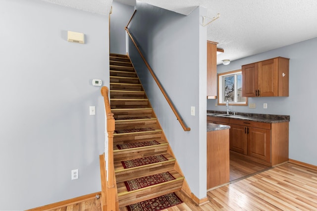 staircase with wood-type flooring, a textured ceiling, and sink