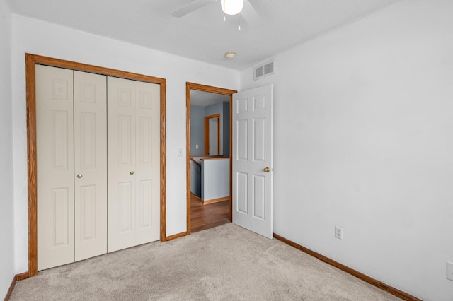 unfurnished bedroom featuring ceiling fan, a closet, and light colored carpet