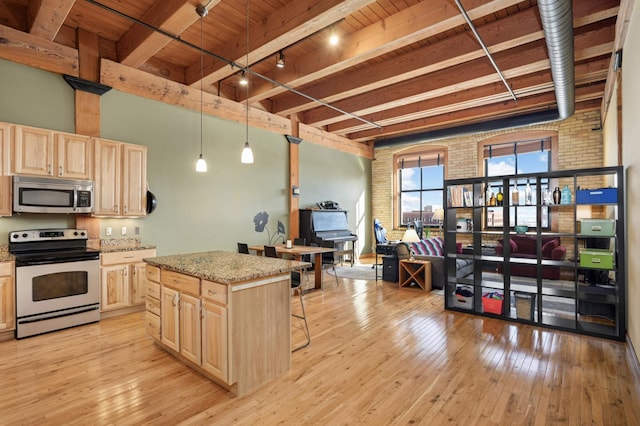 kitchen with appliances with stainless steel finishes, a breakfast bar, open floor plan, a center island, and hanging light fixtures