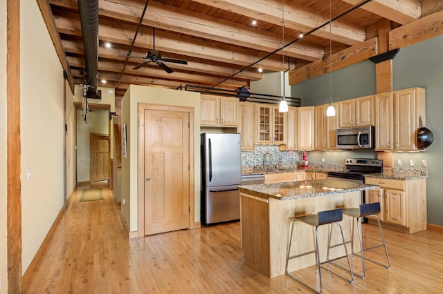 kitchen with glass insert cabinets, stone countertops, appliances with stainless steel finishes, and a center island