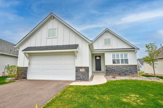 view of front facade with aphalt driveway, a front lawn, board and batten siding, and stone siding