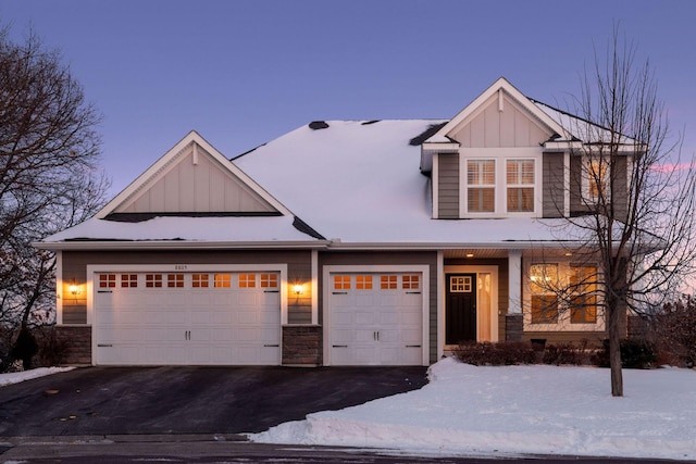 craftsman-style house with a garage, stone siding, aphalt driveway, and board and batten siding