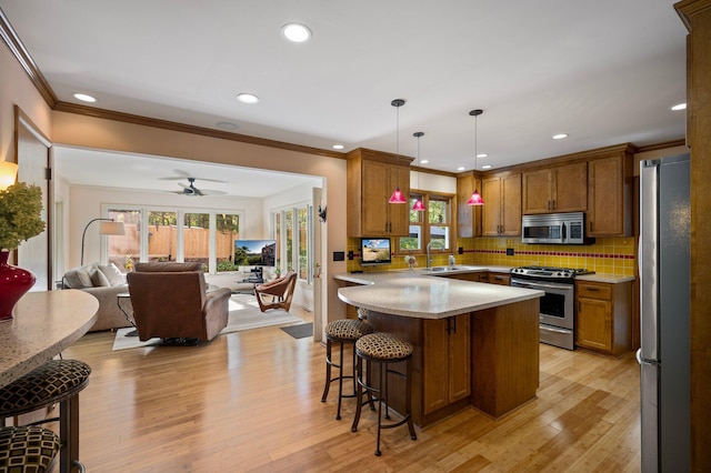 kitchen with a breakfast bar area, stainless steel appliances, hanging light fixtures, open floor plan, and a sink