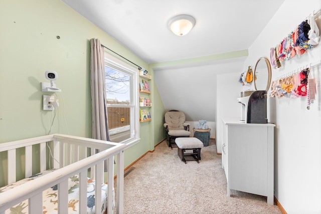 bedroom featuring a crib, light carpet, and lofted ceiling