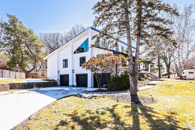 view of property exterior with fence, a garage, driveway, and stucco siding