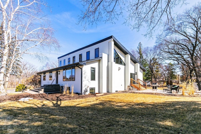 rear view of house featuring stucco siding, a patio, and a lawn