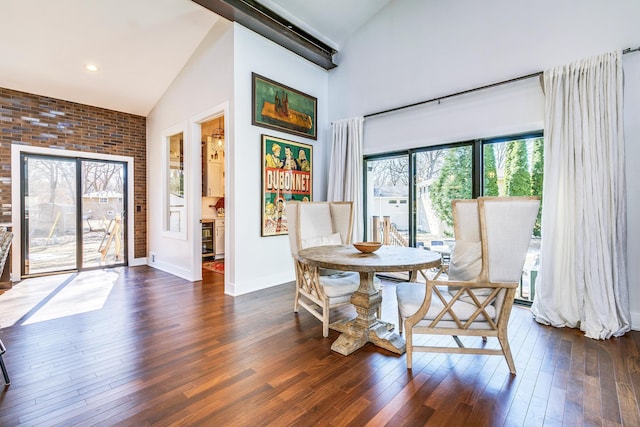 dining room featuring dark wood-type flooring, baseboards, and high vaulted ceiling