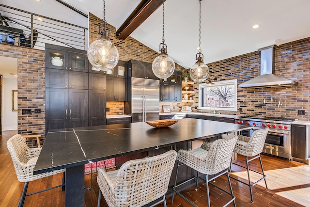 kitchen featuring lofted ceiling with beams, premium appliances, tasteful backsplash, and wall chimney exhaust hood