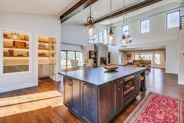 kitchen with stainless steel microwave, a kitchen island, dark wood-type flooring, and open floor plan