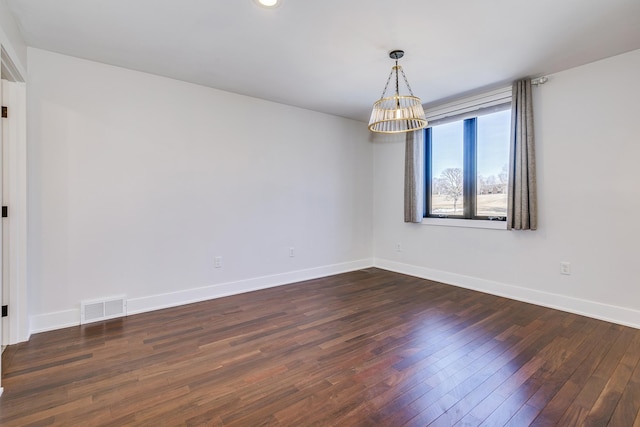 spare room featuring visible vents, baseboards, an inviting chandelier, and dark wood-style flooring