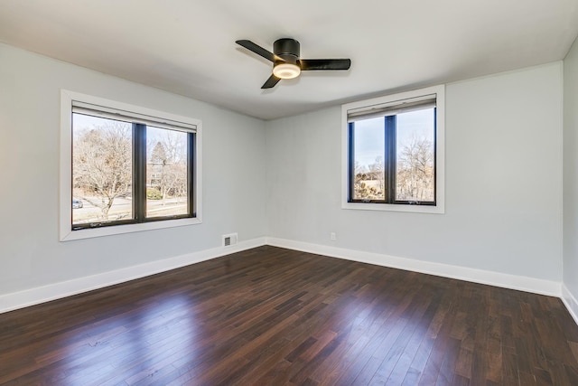 unfurnished room featuring dark wood-type flooring, visible vents, and baseboards