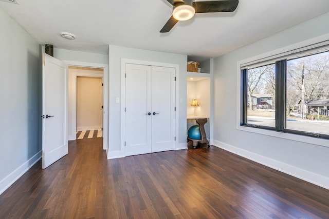 unfurnished bedroom with a ceiling fan, wood finished floors, baseboards, and a closet