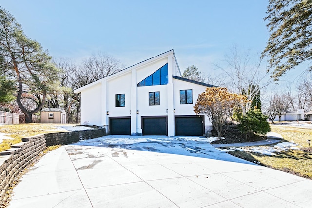 view of home's exterior with a storage unit, stucco siding, driveway, an outdoor structure, and an attached garage