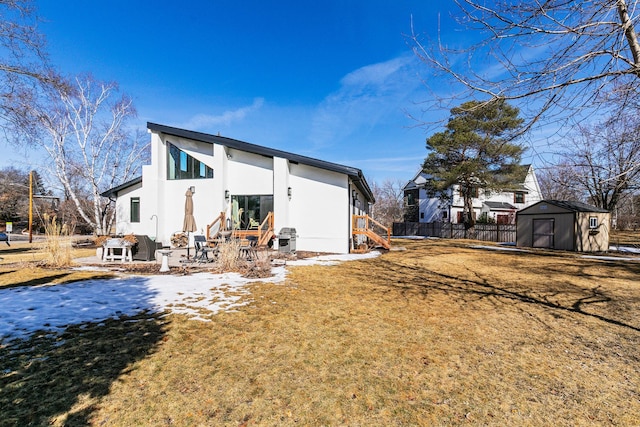 back of property with fence, stucco siding, a lawn, a storage shed, and an outdoor structure