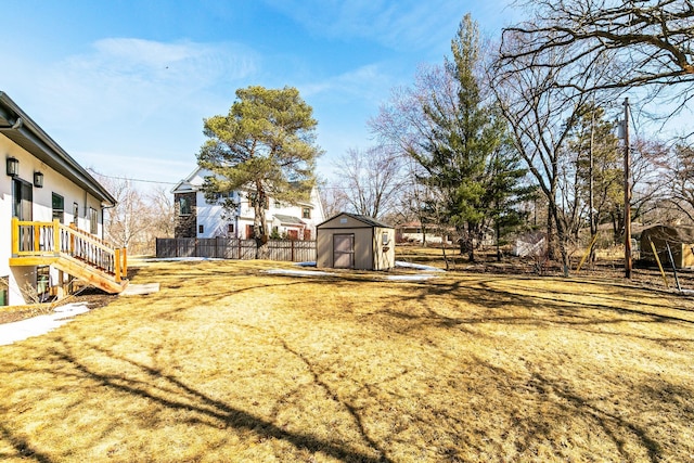 view of yard featuring an outbuilding, a storage shed, and fence