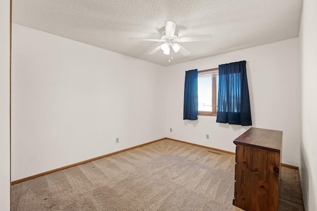 empty room with carpet, visible vents, ceiling fan, a textured ceiling, and baseboards