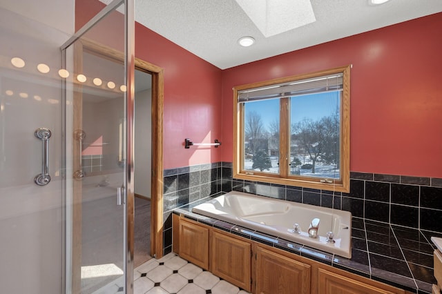 full bath with a textured ceiling, a skylight, a garden tub, and a shower stall