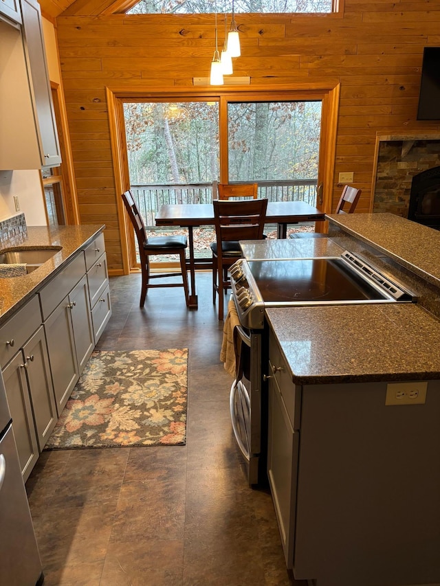 kitchen with stainless steel electric range, wooden walls, and pendant lighting