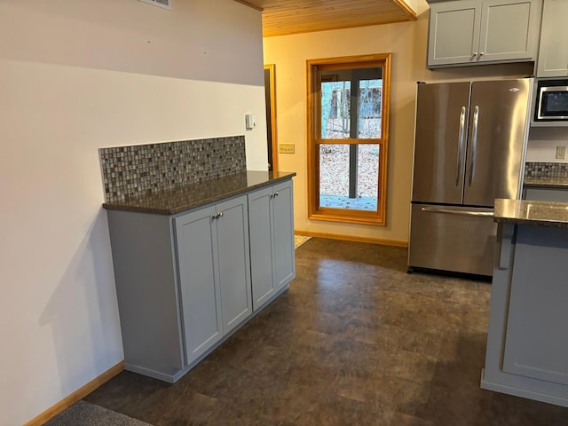 kitchen with appliances with stainless steel finishes, gray cabinetry, decorative backsplash, wooden ceiling, and dark stone countertops