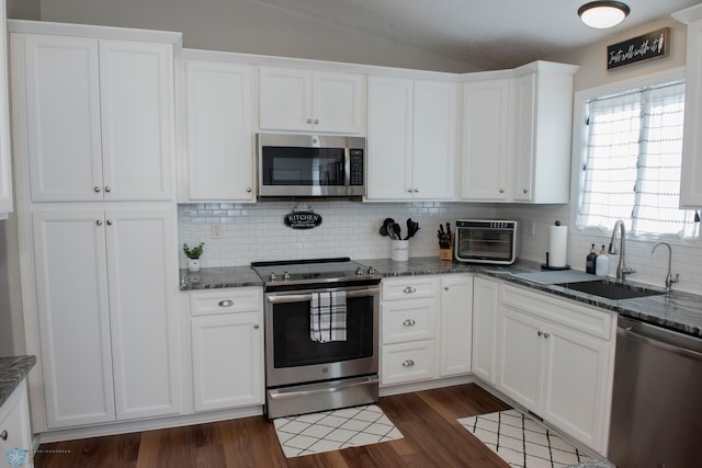 kitchen with appliances with stainless steel finishes, white cabinetry, a sink, and dark wood-style floors