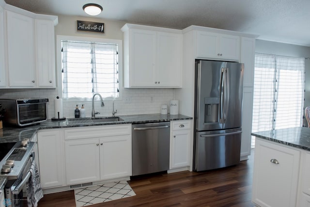 kitchen featuring dark wood-type flooring, white cabinetry, stainless steel appliances, and a sink