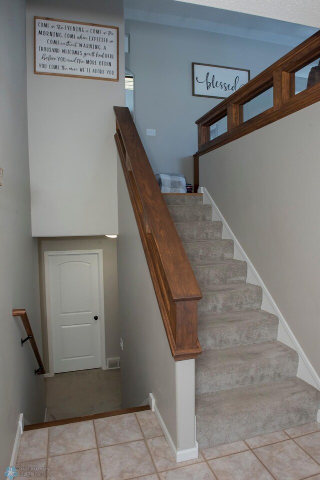 stairway with baseboards, visible vents, and tile patterned floors