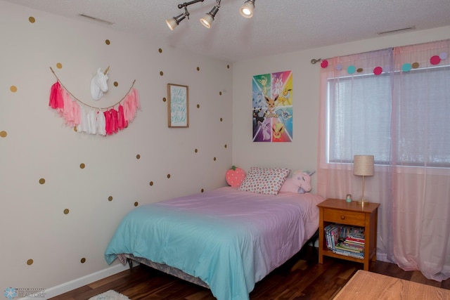 bedroom with dark wood-style floors, baseboards, visible vents, and a textured ceiling