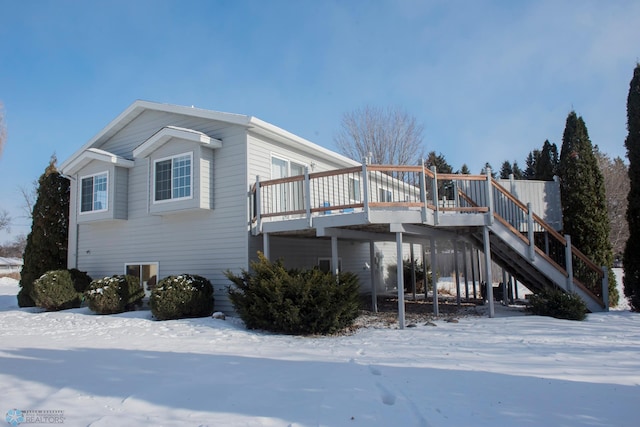 view of snowy exterior featuring stairway and a deck