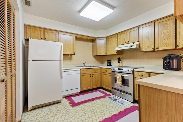 kitchen with white appliances, under cabinet range hood, light countertops, a sink, and tasteful backsplash
